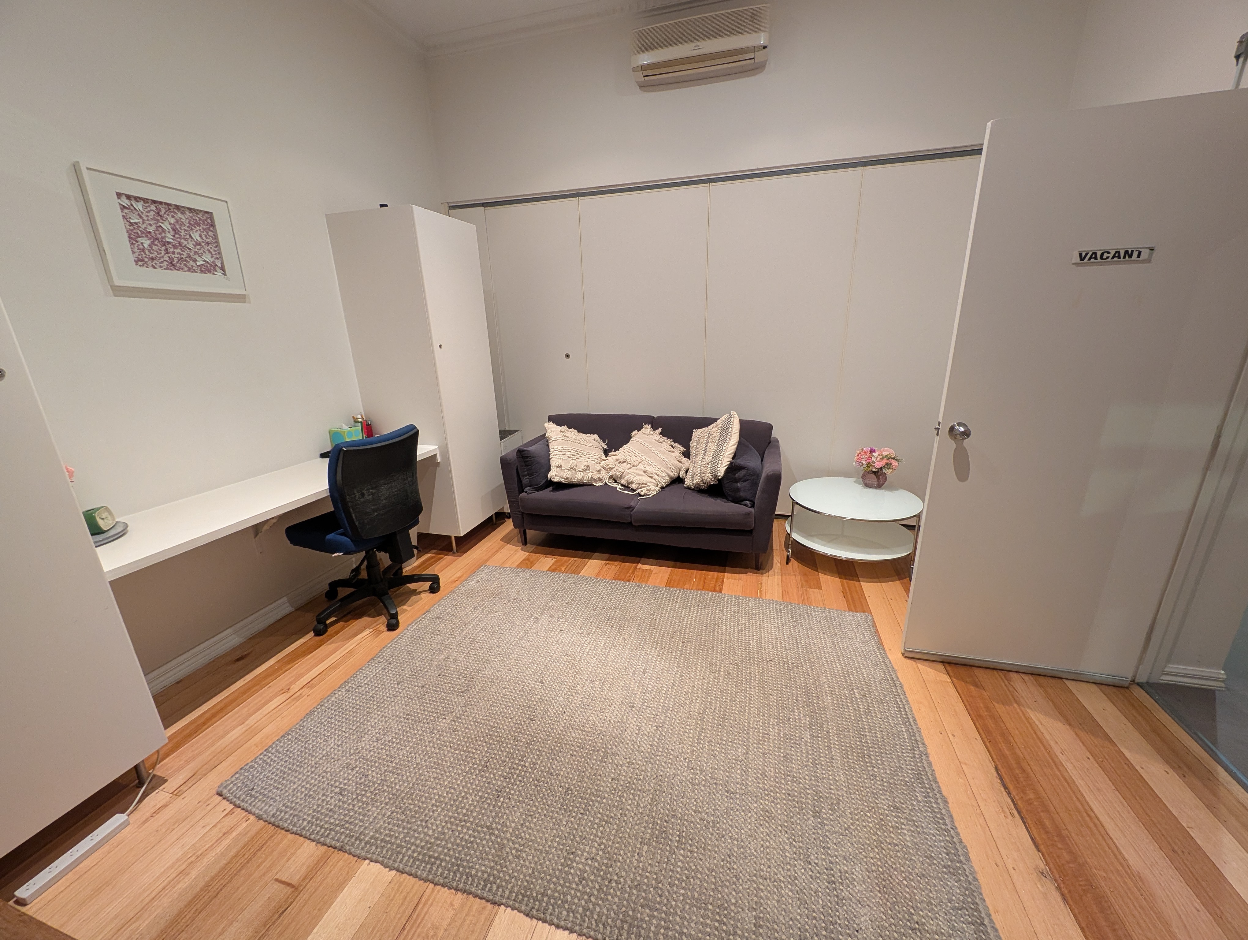 Consulting room at Kew Holistic Health with timber floors and navy sofa